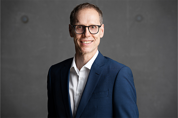 Portraitbild von Markus Stammen Geschäftsführer | Camlog | Camlog Close-up von Markus Stammen vor einer dunkel grauen Betonwand